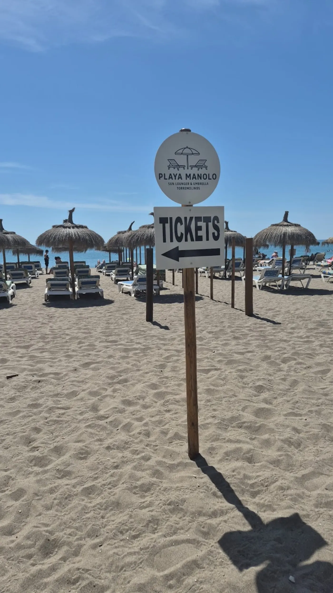 Cartel de Tickets de Playa Manolo clavado en la arena